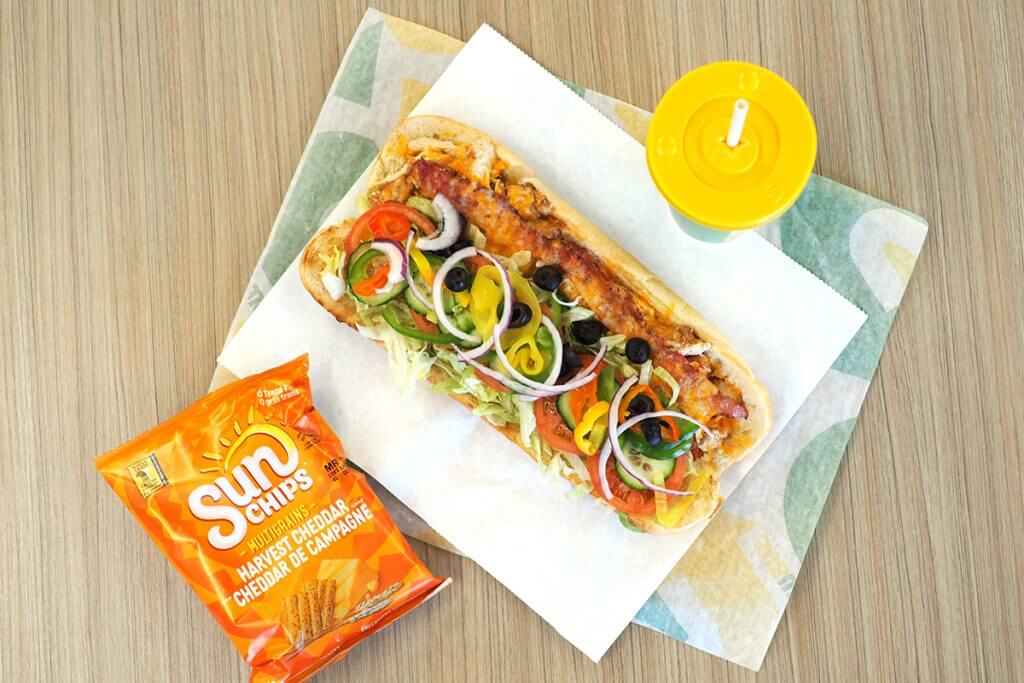 Open-faced subway sandwich with drink and Sun Chips