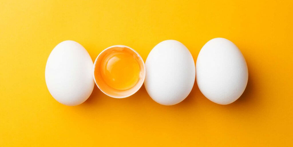 Four eggs in a row against a yellow-orange background
