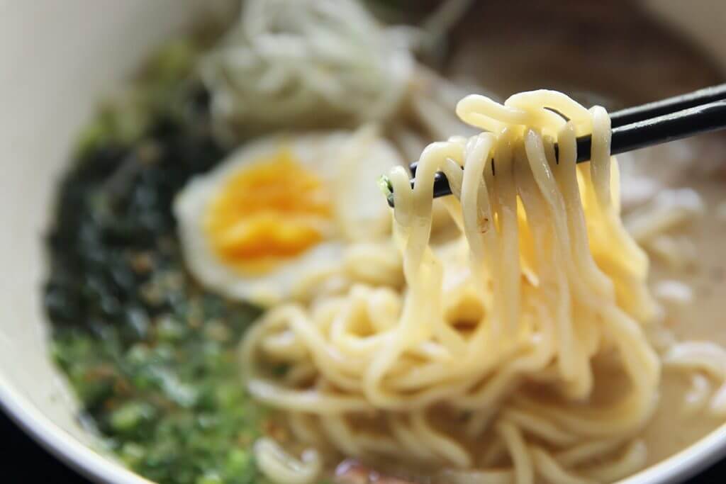 Chopsticks holding up noodles from an Asian dish
