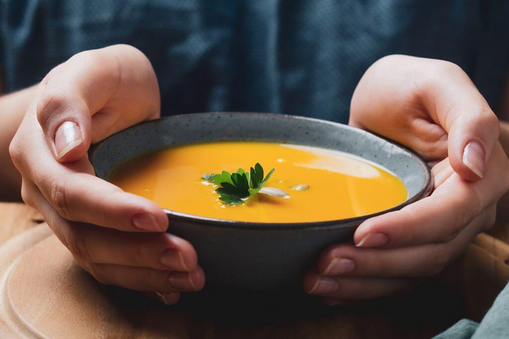 Person holding bowl of soup