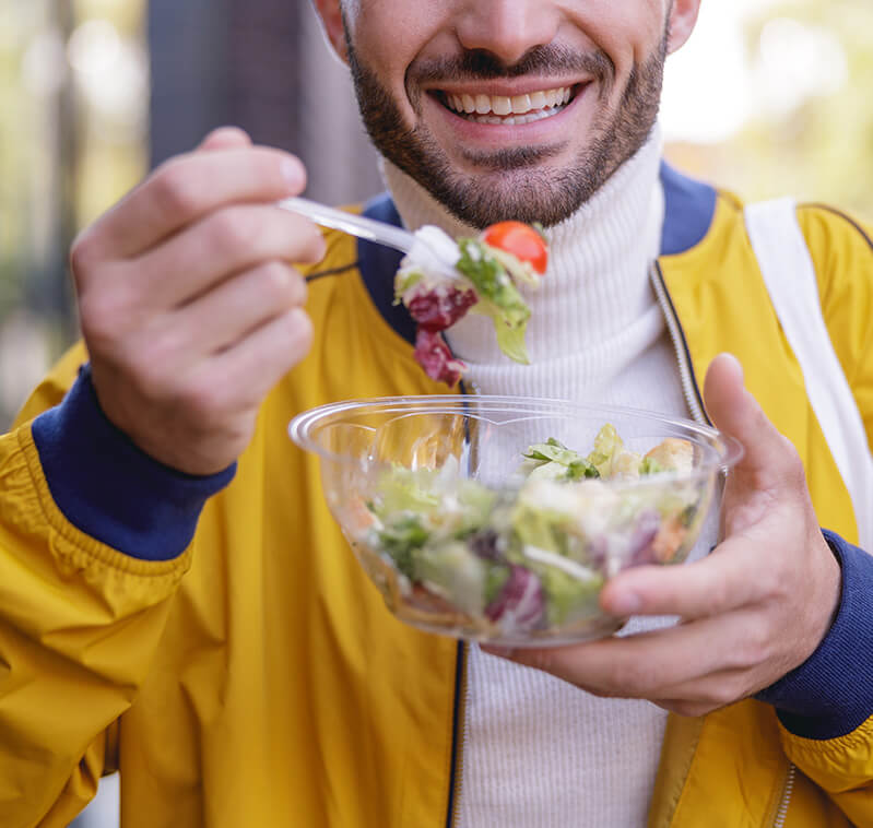 Man smiling while eating a salad