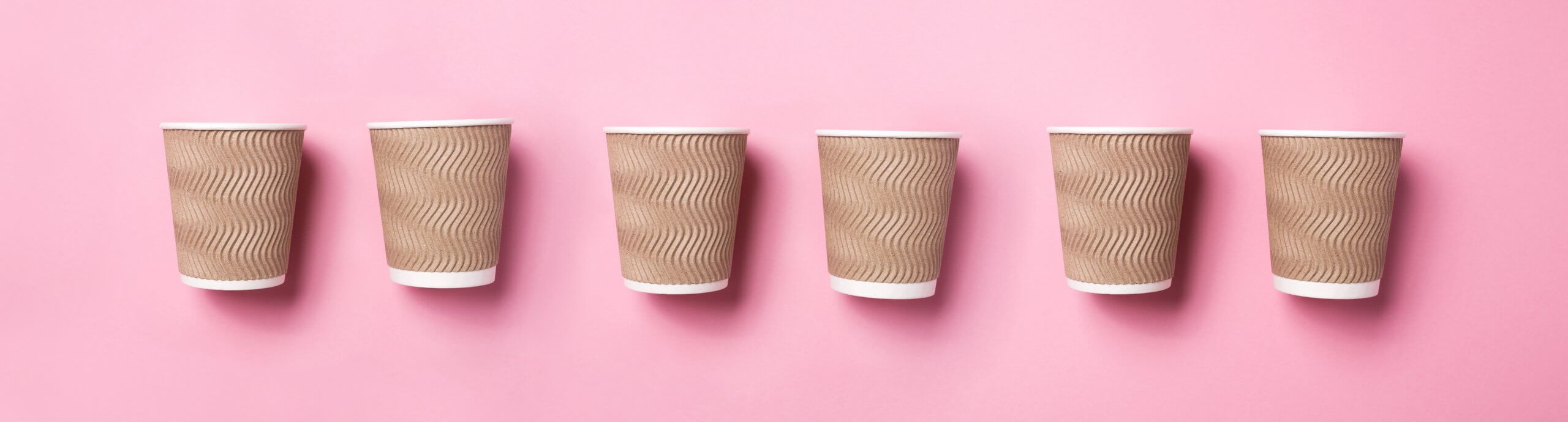 Paper coffee cups on pink background